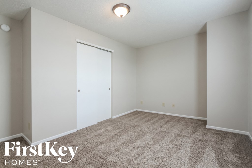 a bedroom with carpet and a door to a closet