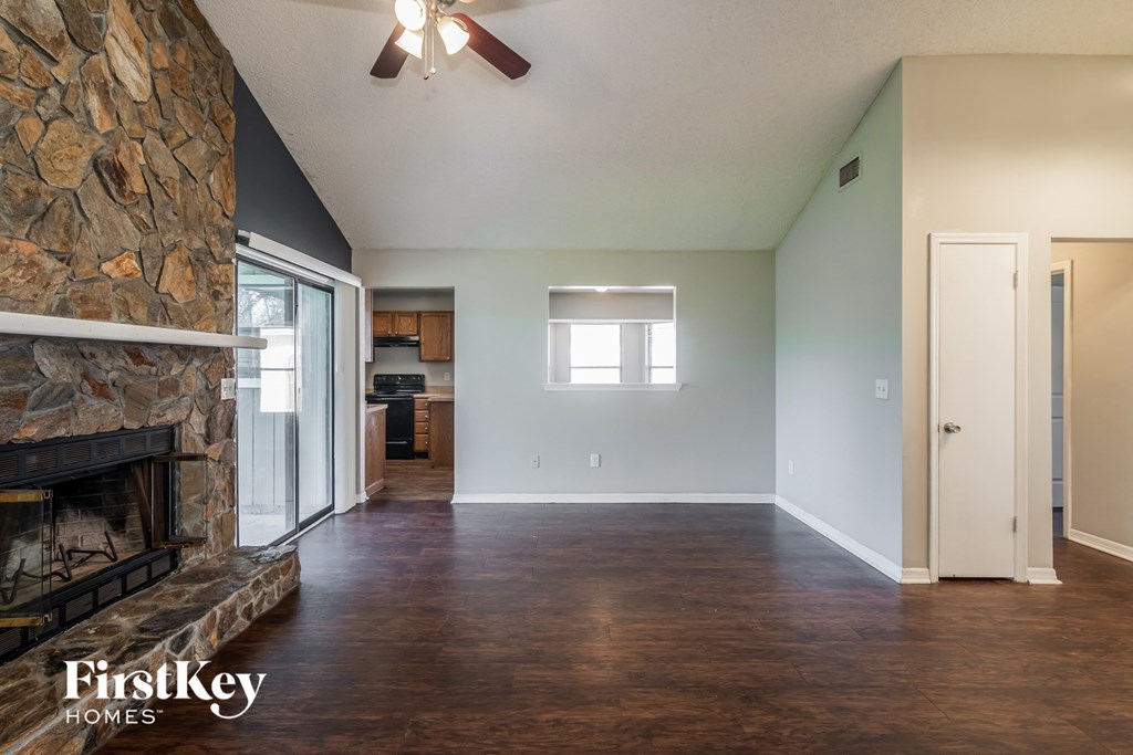 A room with a stone fireplace and wooden floors.