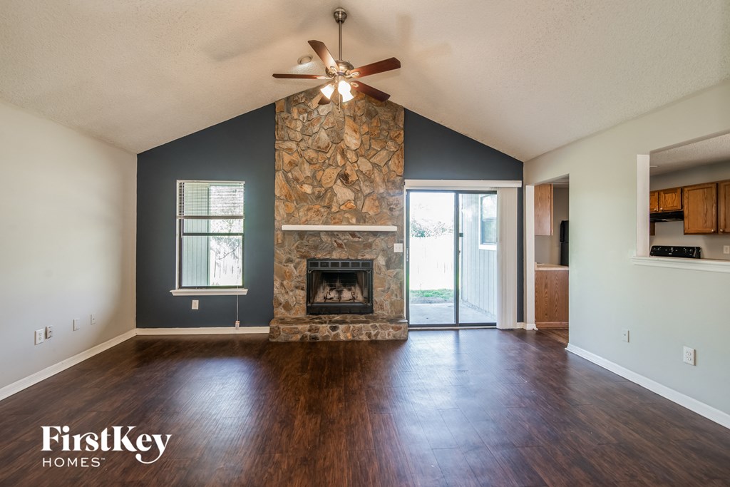 A spacious living room with a fireplace and a ceiling fan.