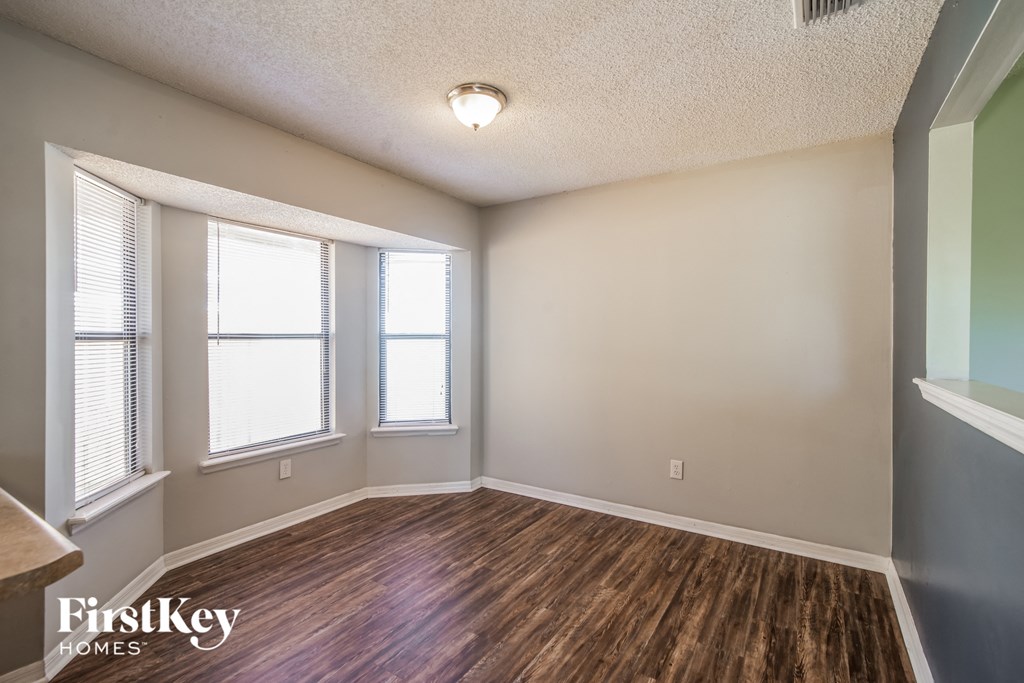 A room with wooden floors and two windows.