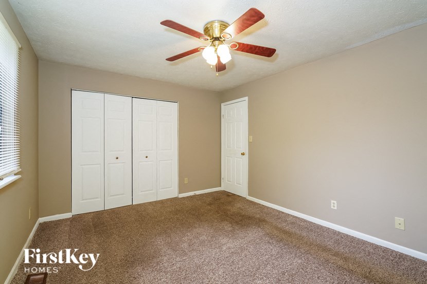 a bedroom with a ceiling fan and two closets