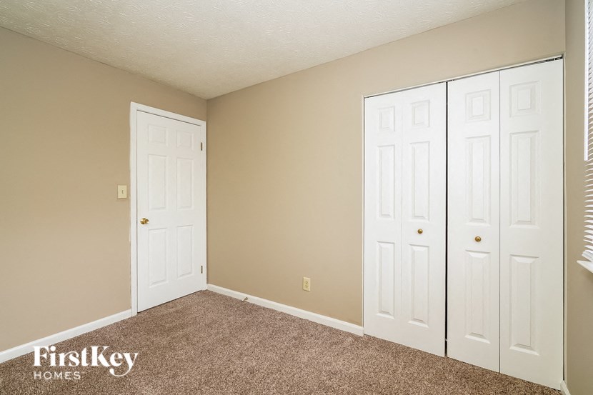 a bedroom with three closets and a carpeted floor