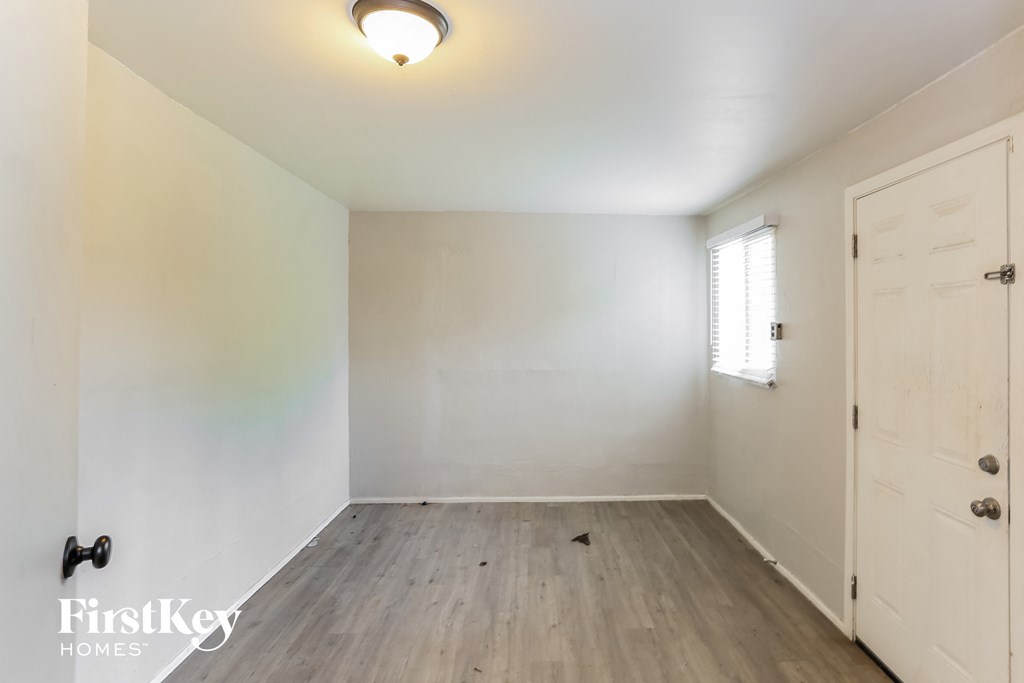 a bedroom with white walls and wood floors and a white door