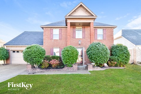 a brick house with a garage and a lawn