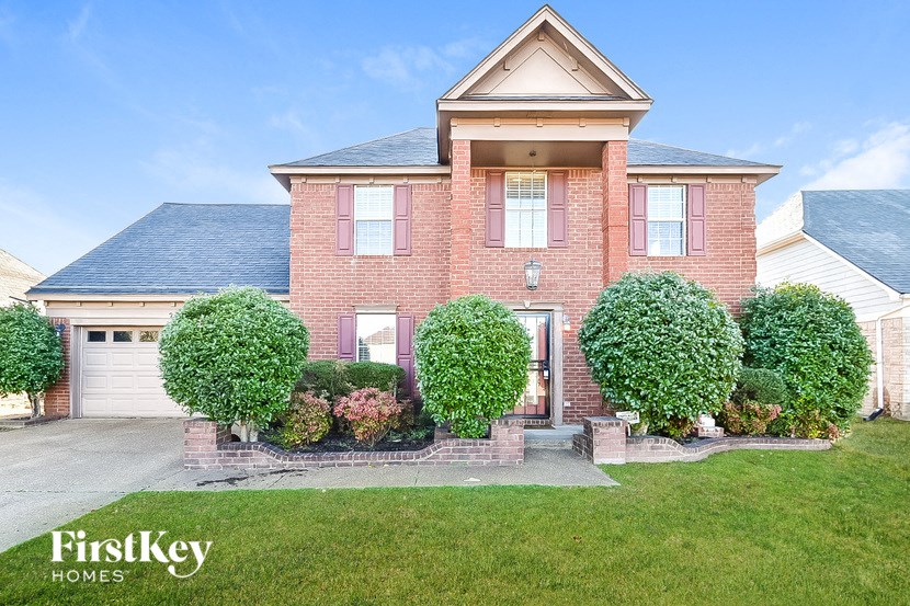 a brick house with a garage and a lawn