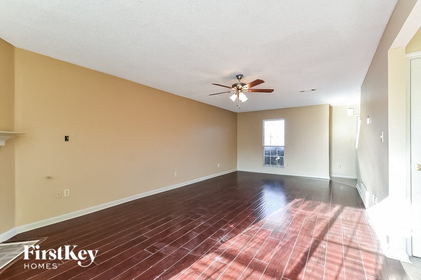 an empty living room with a ceiling fan