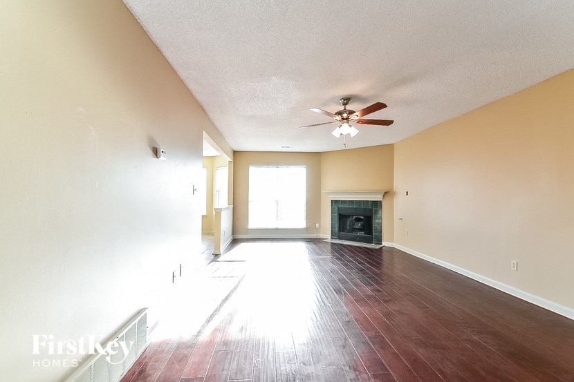 an empty living room with wood floors and a ceiling fan