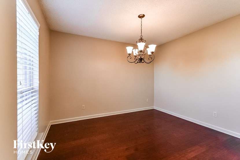 an empty dining room with wood floors and a chandelier