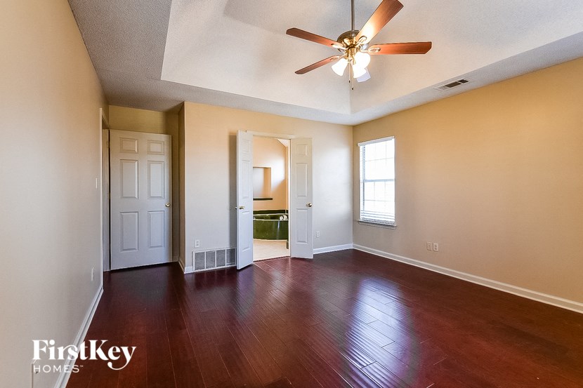 an empty living room with wood floors and a ceiling fan