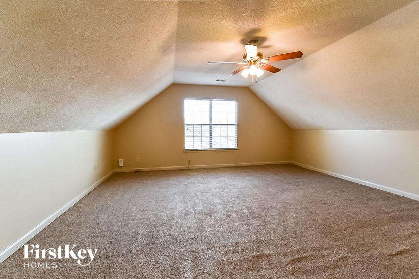 an empty attic with a ceiling fan and a window
