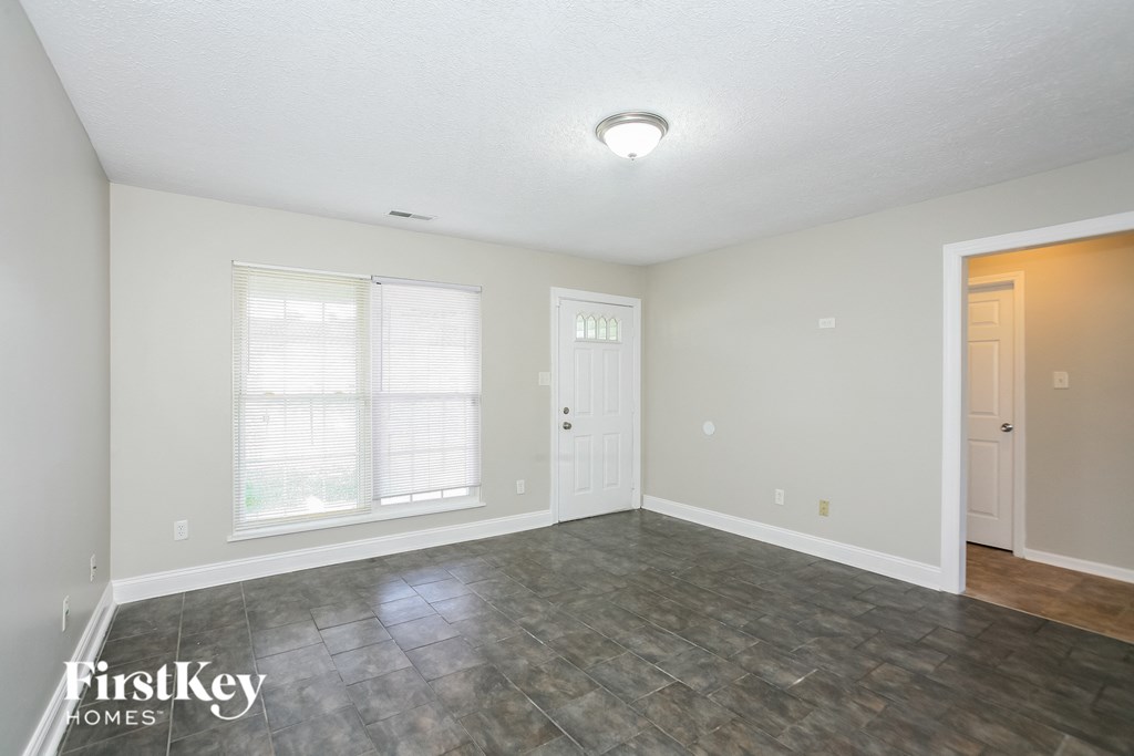 the living room of an empty house with a door and a window