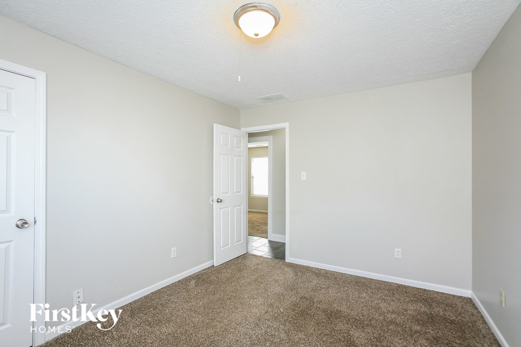 a bedroom with a carpeted floor and a door to a hallway