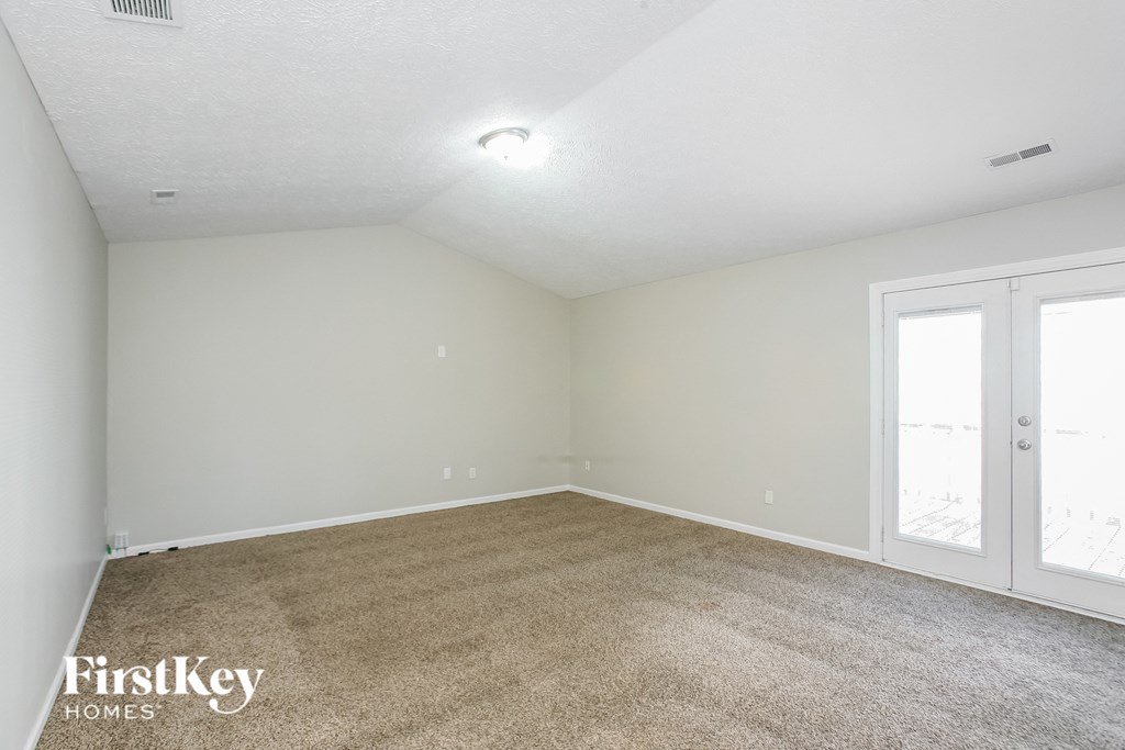 the living room of an empty home with white walls and carpet
