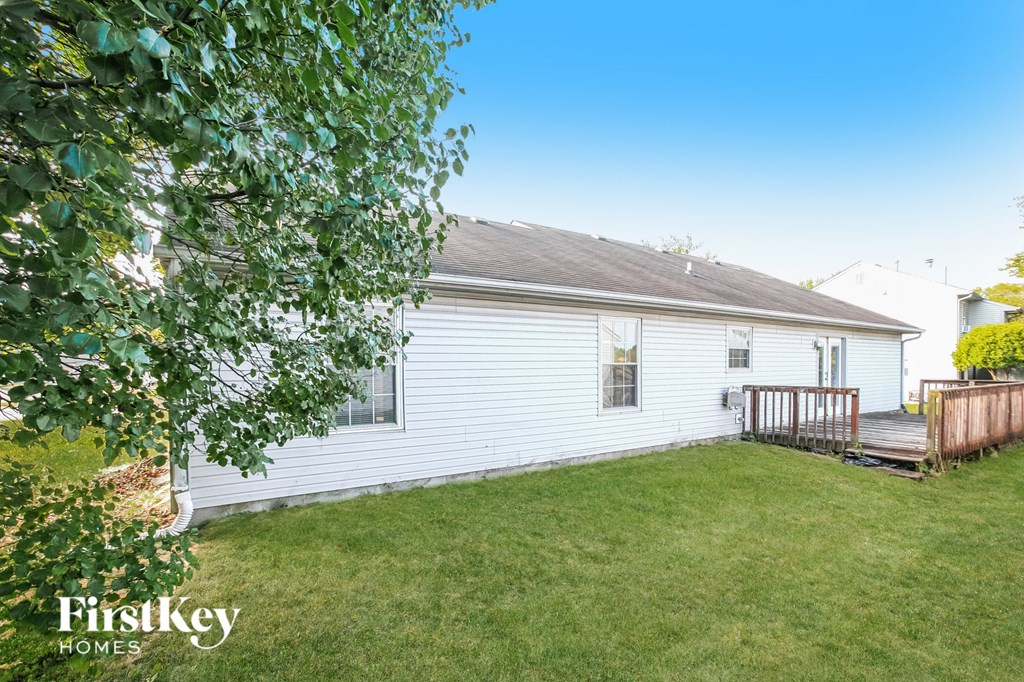 a small white house with a yard and a deck