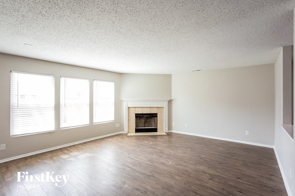 A spacious room with a fireplace and wooden flooring.
