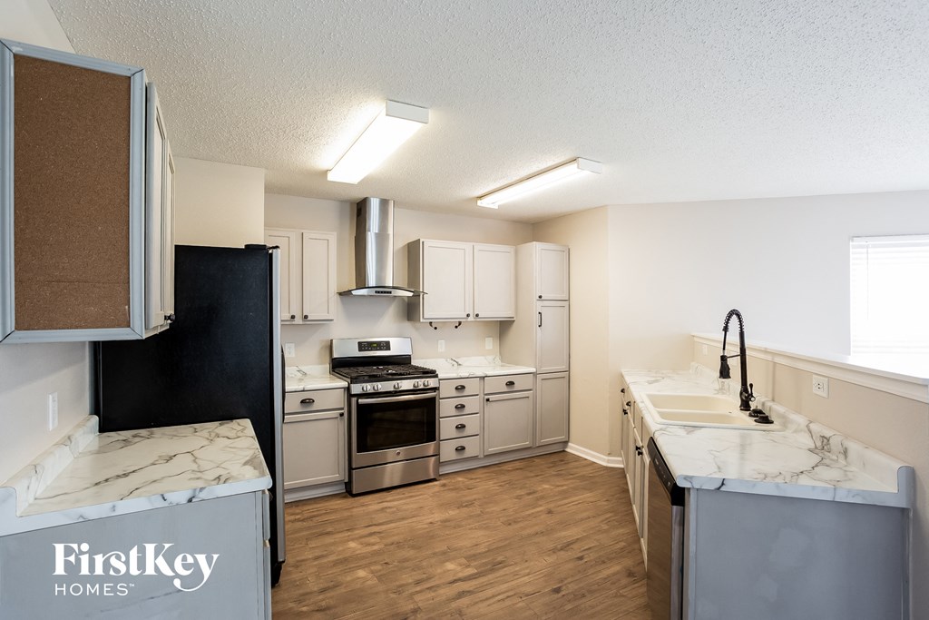 A kitchen with a refrigerator, stove, and sink.