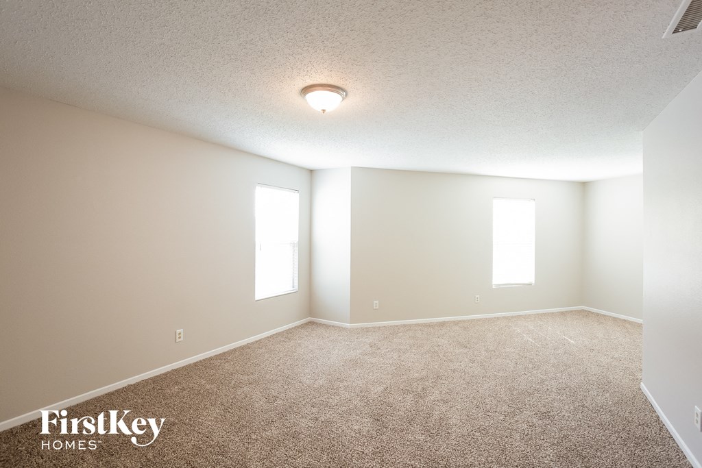 A room with a carpet floor and two windows.