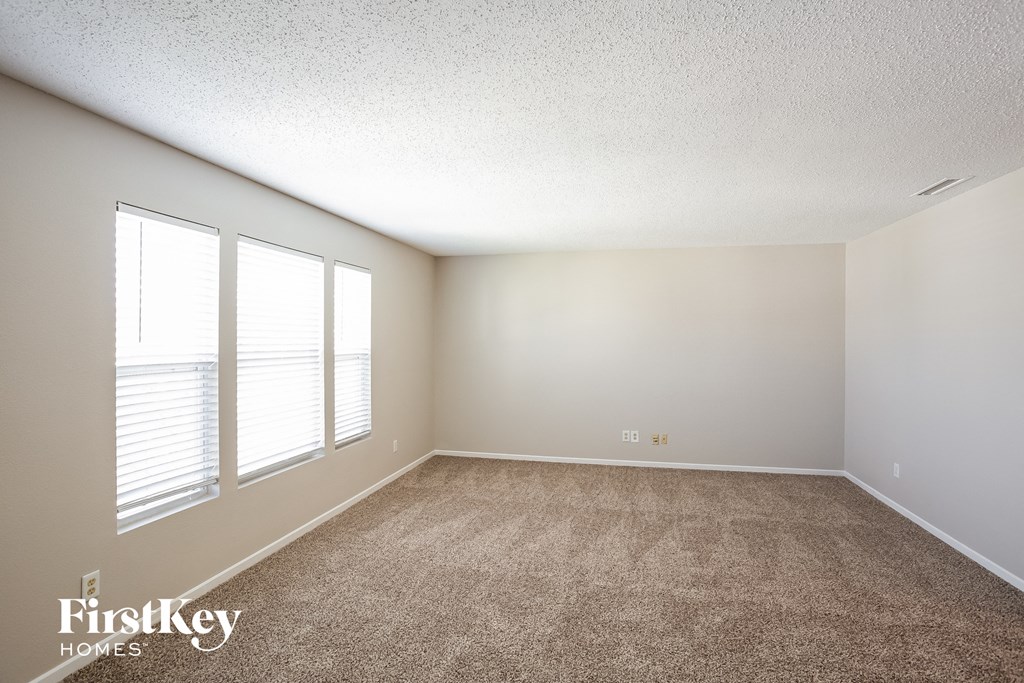 A room with a carpeted floor and a window with blinds.