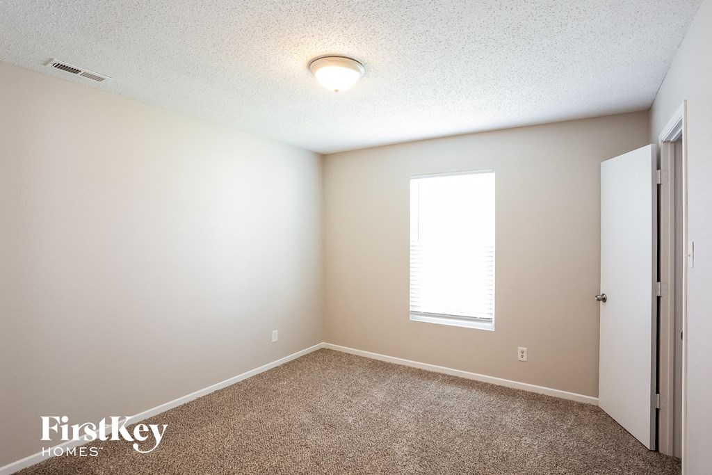 A room with a carpeted floor and a window with blinds.