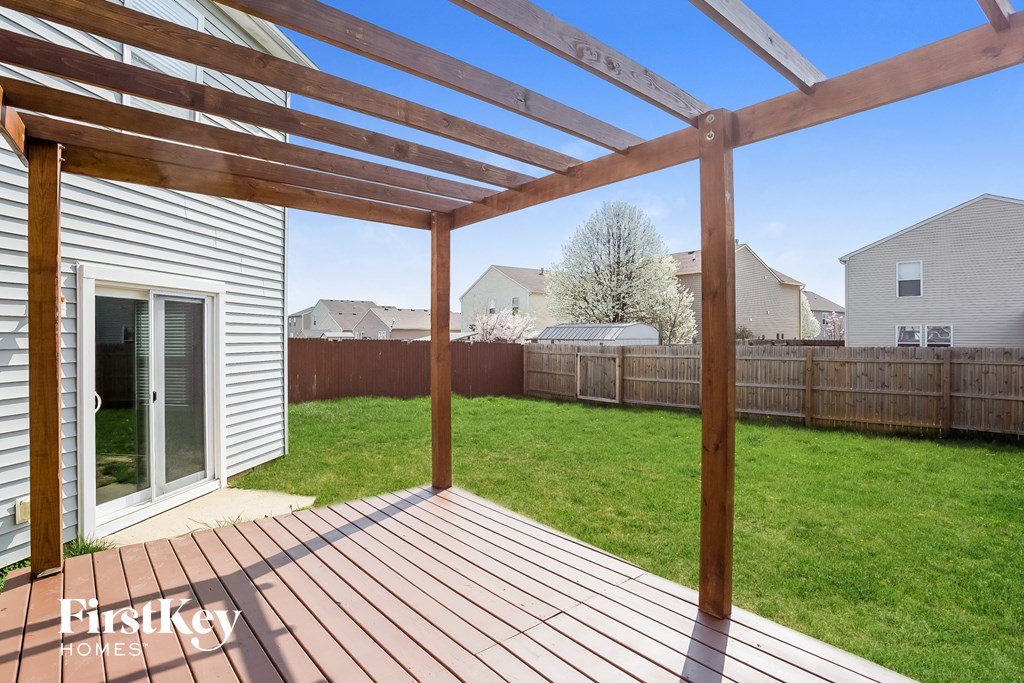 A wooden pergola over a wooden deck in a sunny backyard.