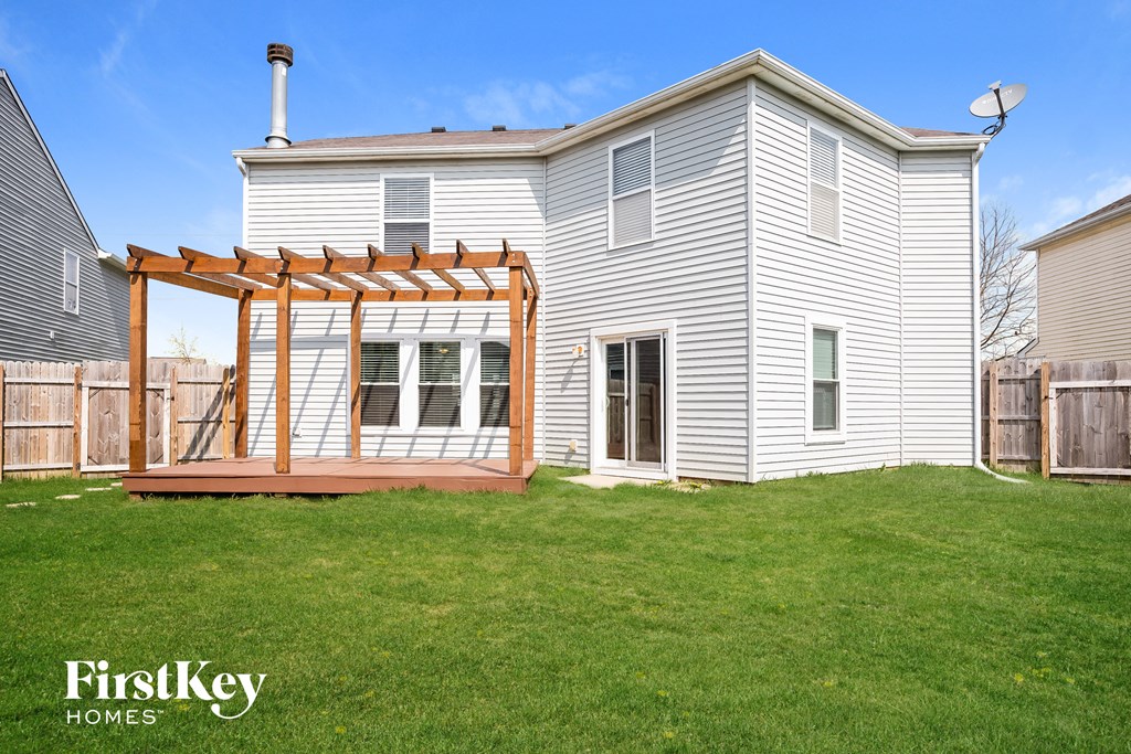 A house with a wooden pergola attached to it.