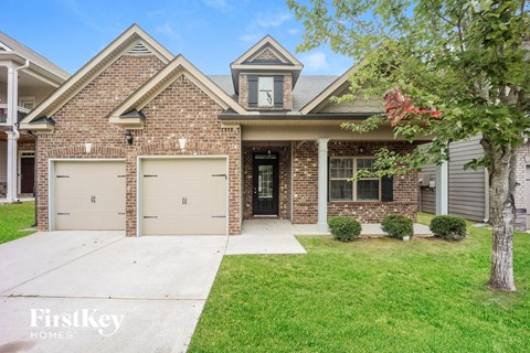a brick house with two garage doors and a sidewalk