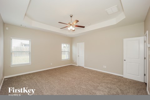 the master bedroom has a ceiling fan and a carpeted floor