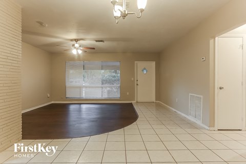 an empty living room with a large window and a hard wood floor
