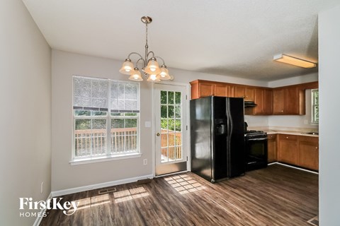 an empty kitchen with a black refrigerator and a window