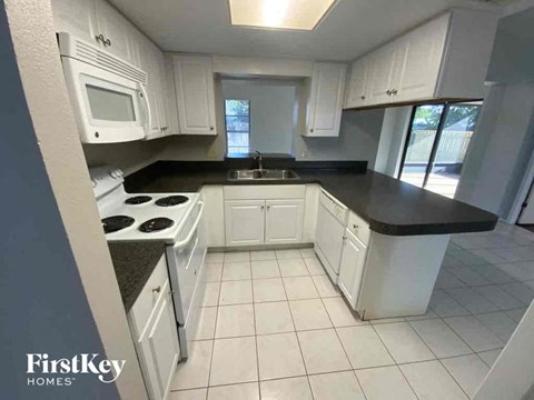 A kitchen with white cabinets and black countertops.