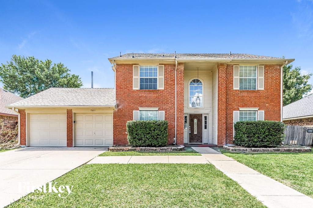 a brick house with two garage doors and a lawn