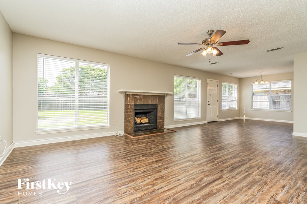 an empty living room with a fireplace and a ceiling fan