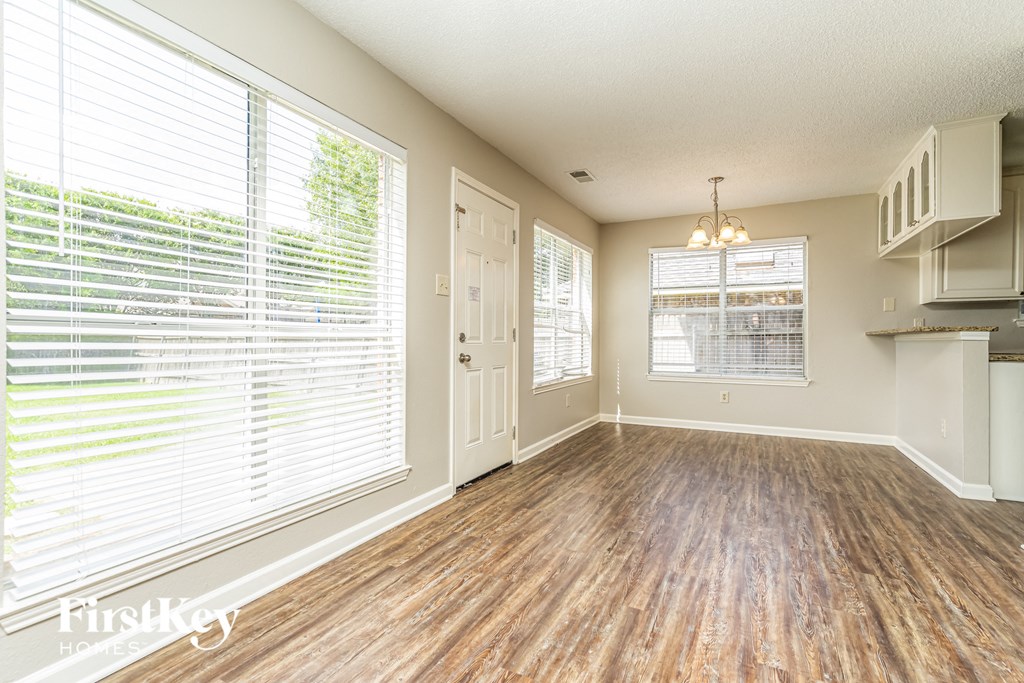 an empty living room with a large window and a kitchen