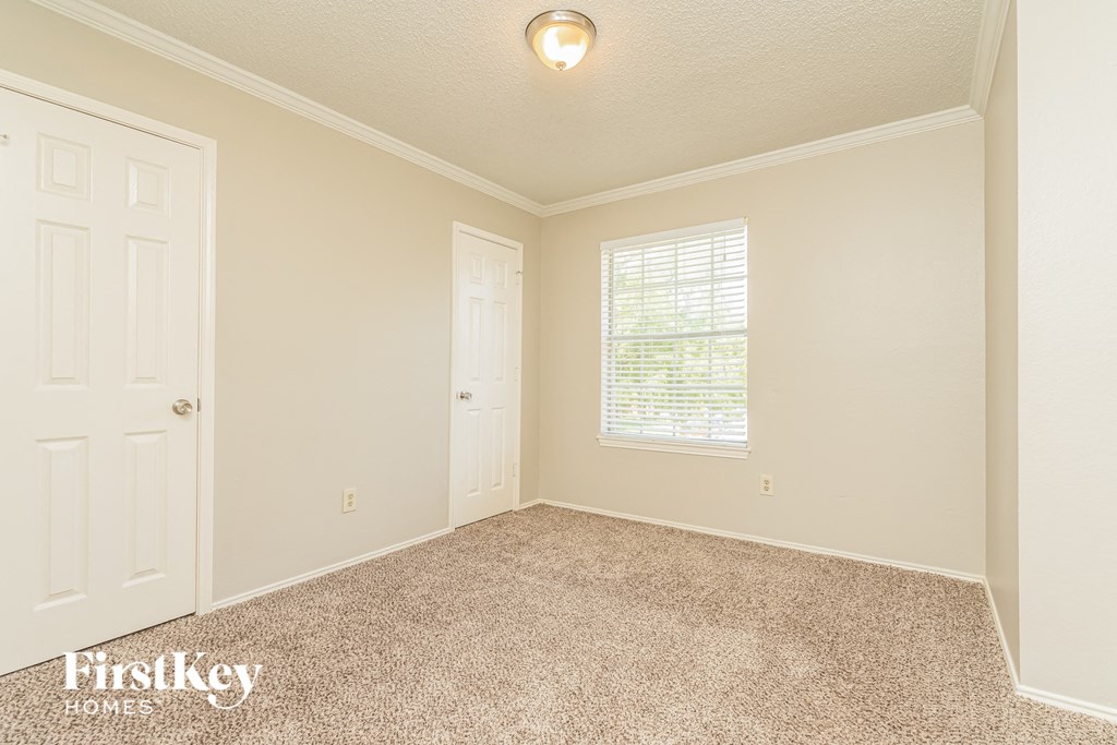 a bedroom with carpet and a door and a window