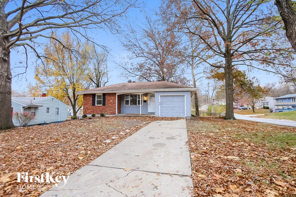 A house with a driveway in front of it surrounded by trees.