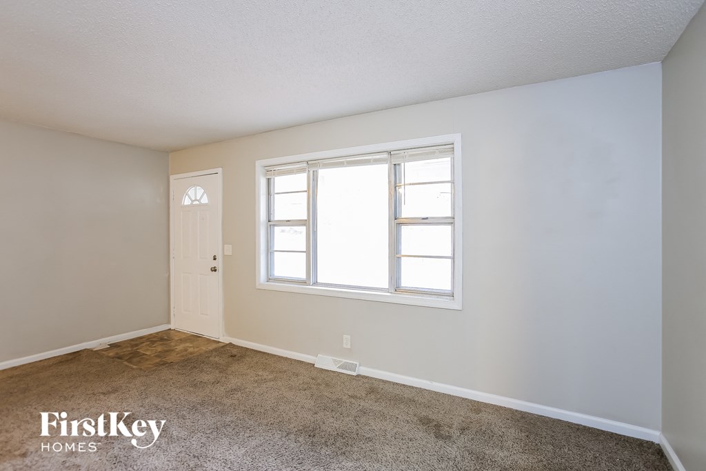 A room with a carpeted floor, a door, and a window.