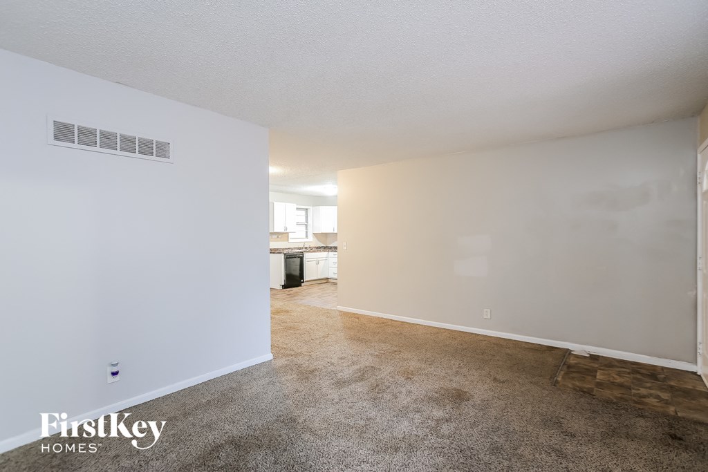 A room with a carpeted floor and a wall with a FirstKey Homes logo.
