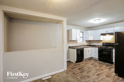 A kitchen with black appliances and wooden floors.