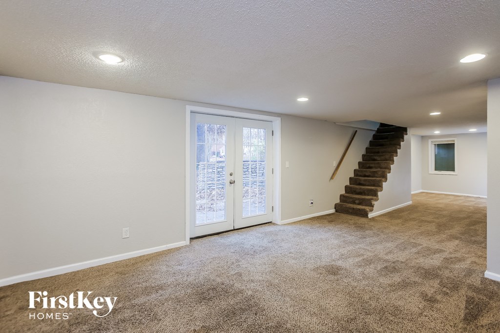 A spacious room with a staircase and a carpeted floor.