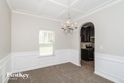 a dining room with white walls and a chandelier