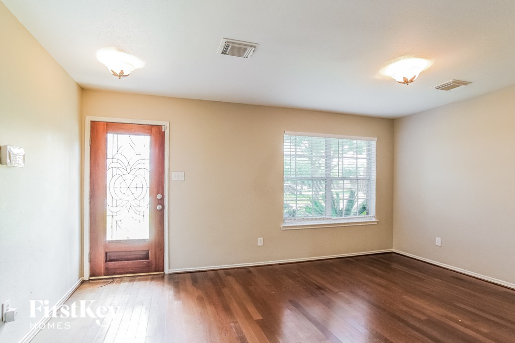 A room with a wooden floor and a red door.