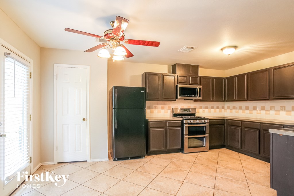 A kitchen with a fan and a fridge.