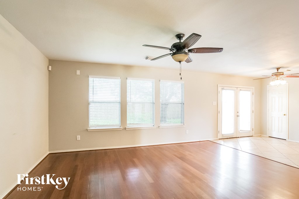 A room with a fan and wooden floors.