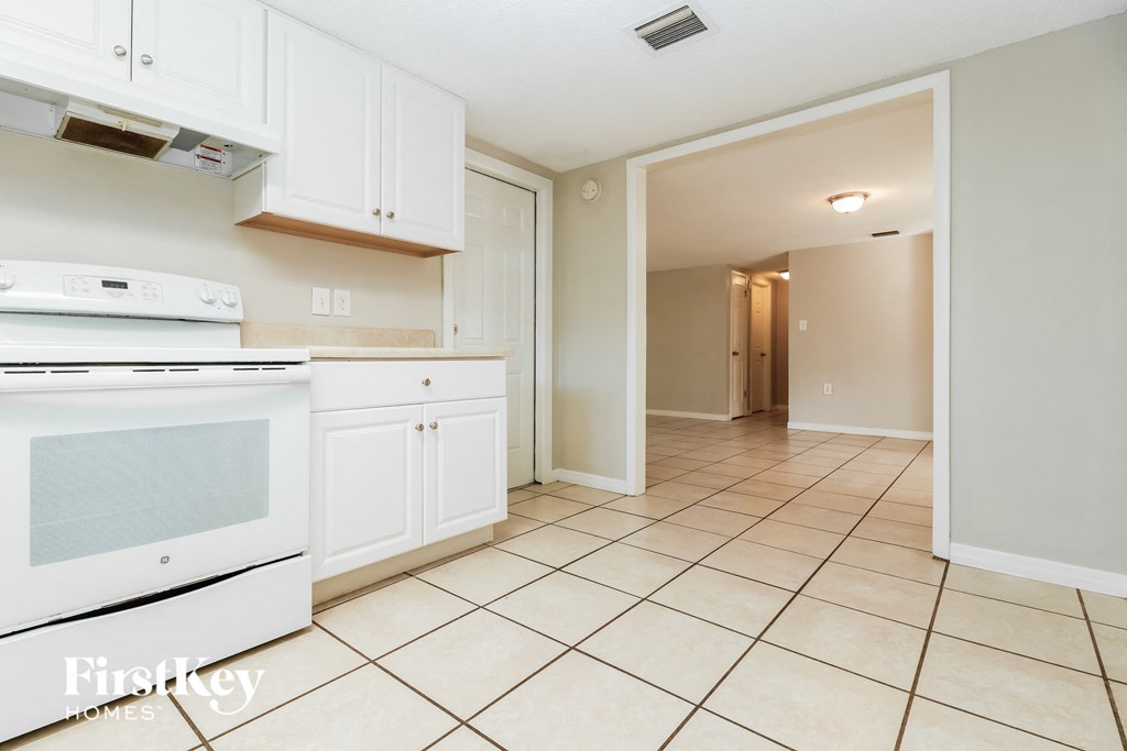 a kitchen with white cabinets and white appliances and tiled floors