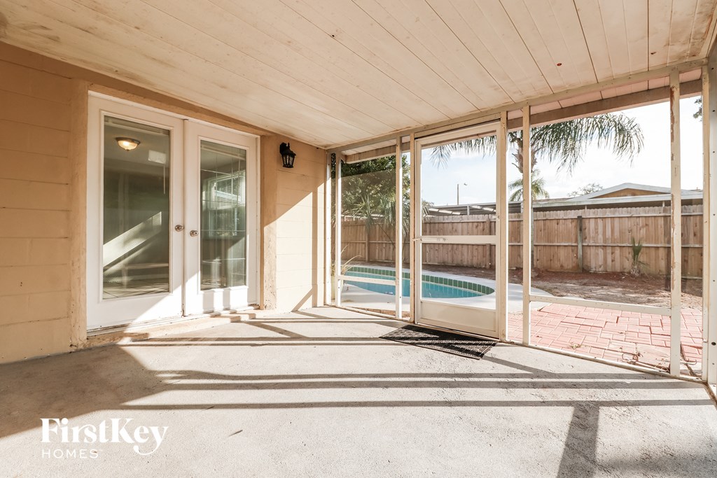 a covered porch with a pool and sliding glass doors
