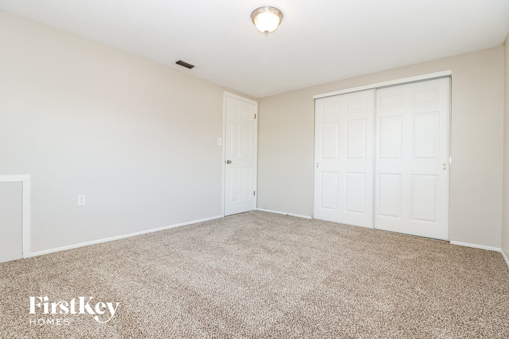 a spacious living room with carpet and white doors