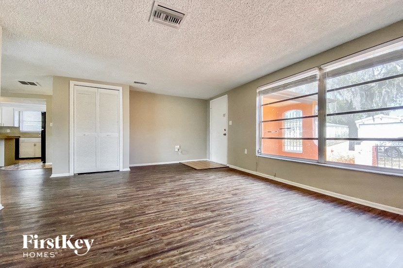 an empty living room with a large window and wood floors