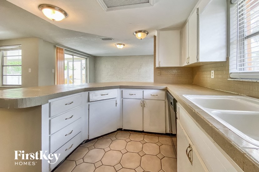 a kitchen with white cabinets and a sink and a window