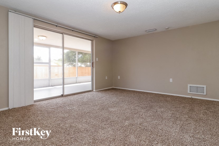 an empty living room with sliding glass doors to a patio