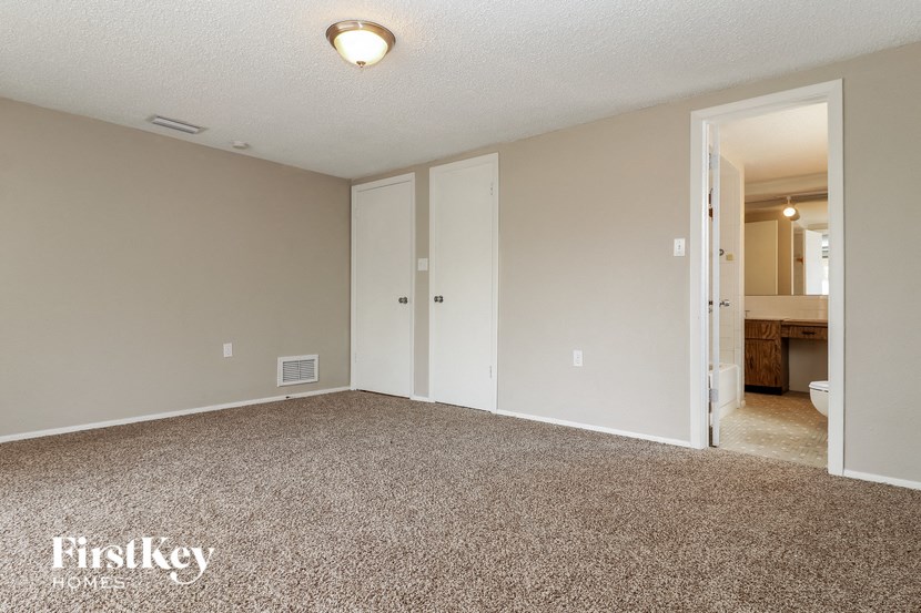 an empty living room with carpet and a door to a bathroom